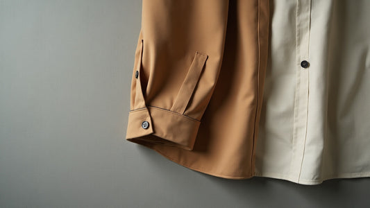 Flat lay of a camel cotton shirt showing collar roll and cuff detail in soft natural window light.