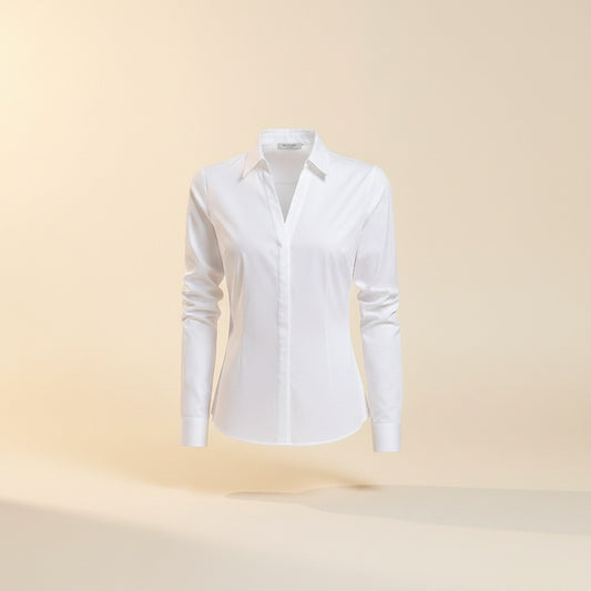White long-sleeve cotton-blend shirt styled with taupe trousers, photographed in a warm, softly lit quiet-luxury studio setting.