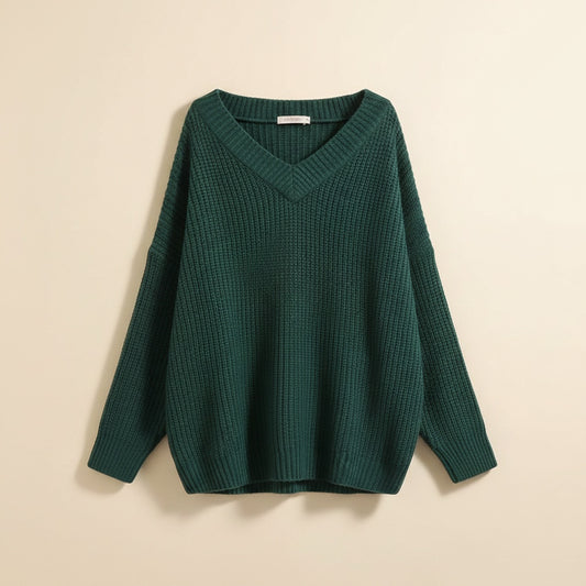 Oversized forest green ribbed knit V-neck pullover with dropped shoulders and relaxed batwing sleeves, styled with tailored trousers.