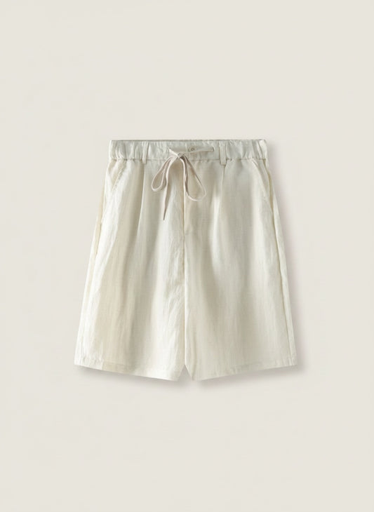 Ivory tailored linen-blend shorts styled with a ribbed tank, photographed in soft villa daylight for a quiet coastal summer look.