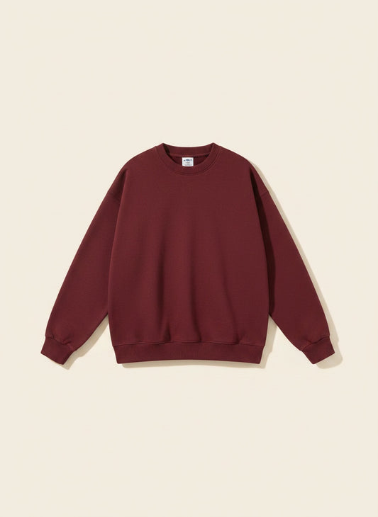 Woman in a burgundy oversized heavyweight loopback crewneck sweatshirt with ribbed cuffs and hem, styled with tonal trousers.