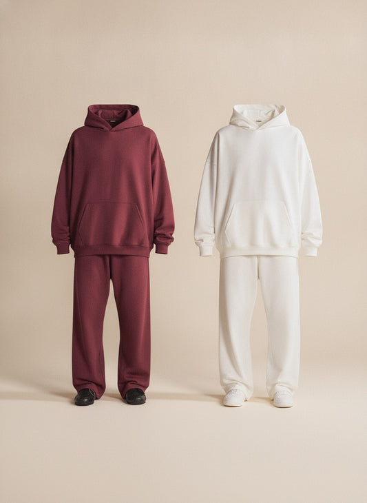 Woman in burgundy hooded loungewear set with kangaroo pocket, styled on a warm off-white studio backdrop.