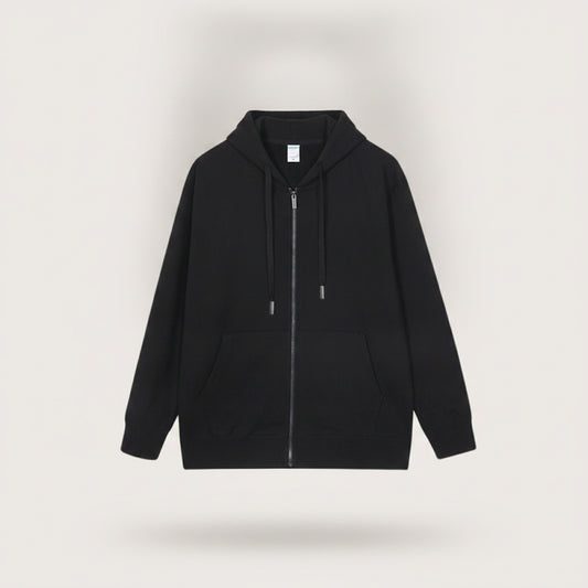Woman in black zip-up hoodie with silver drawcord tips, styled with stone tapered trousers against a warm off-white studio wall.