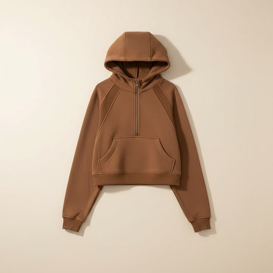 Cropped half-zip hoodie in warm tobacco brown loopback cotton, styled with cream wide-leg trousers in a soft studio setting.