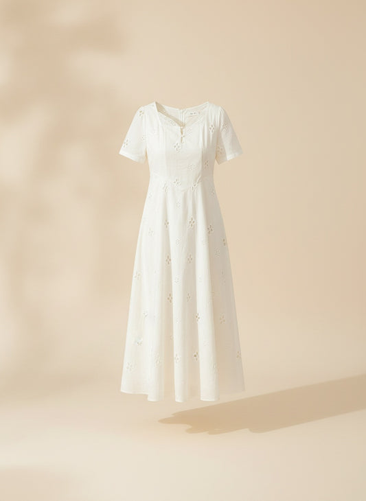 Ivory broderie anglaise midi dress with eyelet floral cutwork, short sleeves and softly nipped waist in warm daylight.