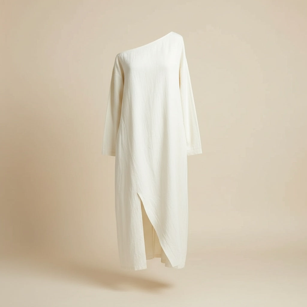 Ivory cotton-linen midi dress with relaxed column silhouette, long sleeves and front slit, styled in soft editorial light.