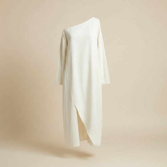 Ivory cotton-linen midi dress with relaxed column silhouette, long sleeves and front slit, styled in soft editorial light.