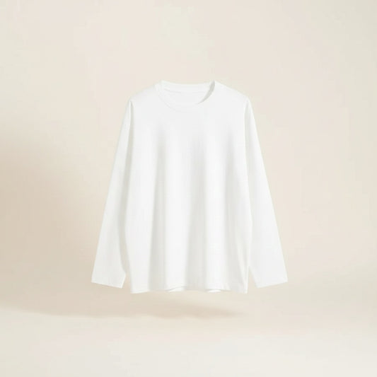 Woman in ivory long-sleeve crewneck tee tucked into taupe wide-leg trousers, soft daylight against warm plaster wall.
