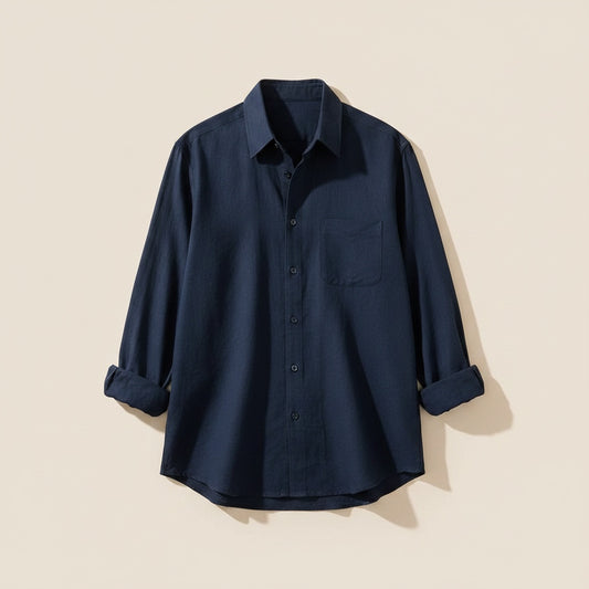Navy long-sleeve shirt with point collar, chest pocket and tonal buttons, styled with relaxed neutral trousers.