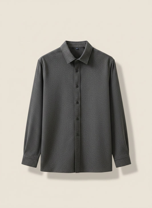 Charcoal collared button-front shirt styled with stone trousers, photographed in a warm off-white studio with soft daylight.