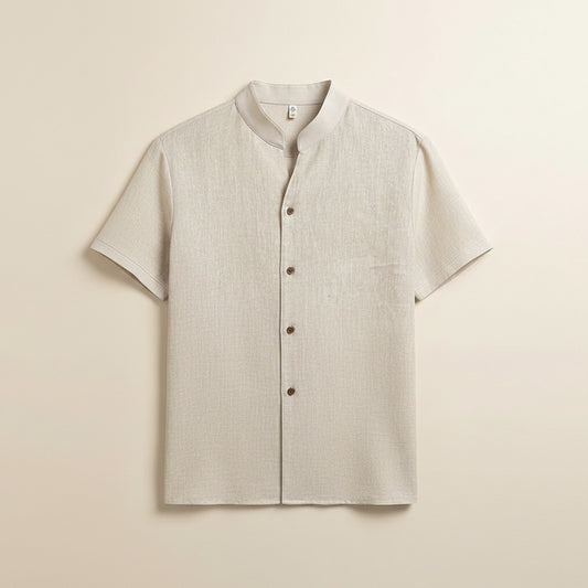 Ivory short-sleeve shirt styled with taupe tapered trousers, photographed in soft warm studio light for a quiet-luxury summer look.