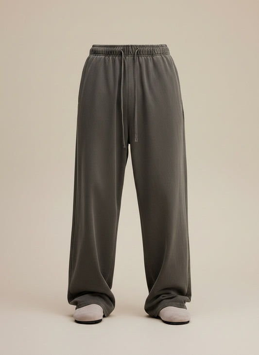 Washed olive-grey heavyweight cotton drawstring trousers with relaxed straight leg, styled with a ribbed ecru tank in soft daylight.