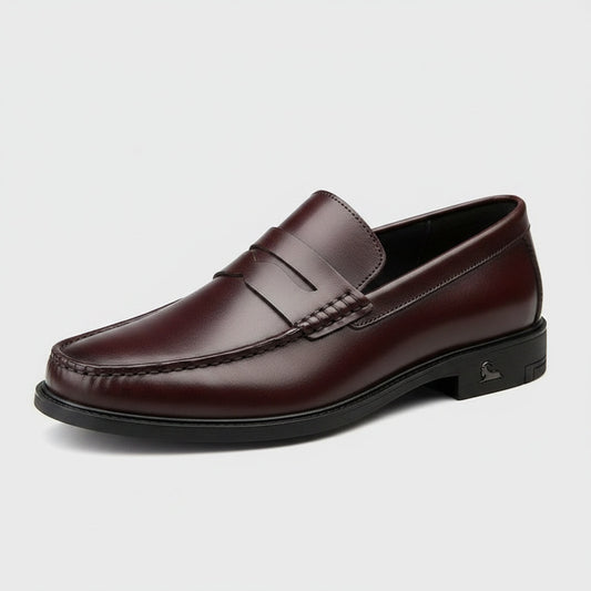 Oxblood burgundy leather penny loafer with moc-toe stitching and low stacked heel, shown in three-quarter view on stone.