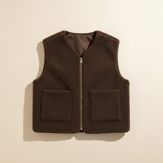 Cropped brown zip-front vest with two front patch pockets and V-neckline, styled in a minimal studio portrait.