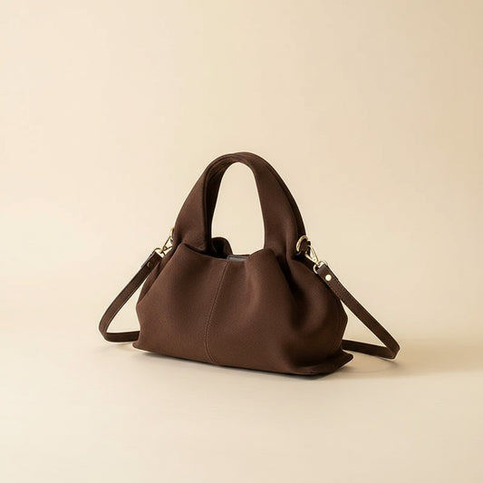 Espresso brown ruched cloud handbag in soft suede with rounded top handle and slim shoulder strap, styled on warm ivory.