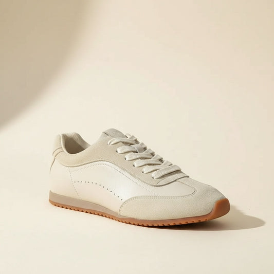 Cream low-profile lace-up sneakers with ivory leather panels, tonal laces, side perforations, and warm gum cupsoles.