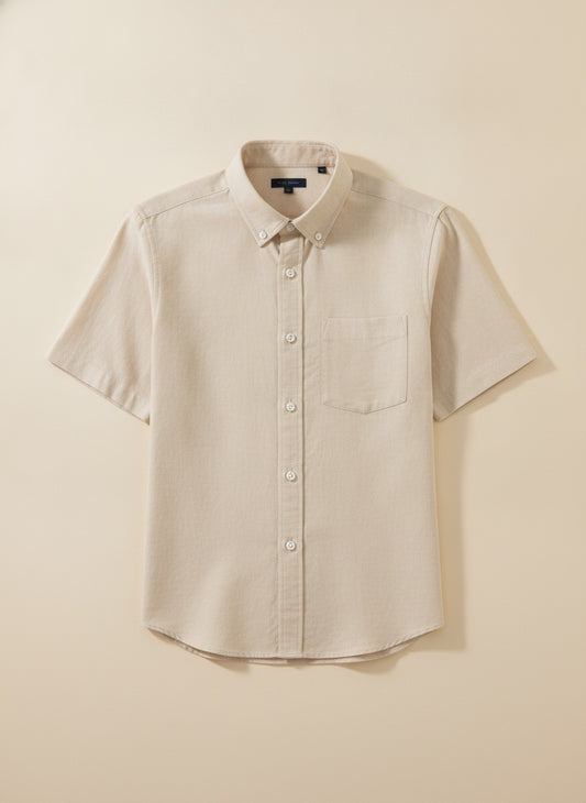 Ecru short-sleeve button-down shirt in lyocell-linen-cotton blend, styled with stone trousers against a warm off-white studio wall.