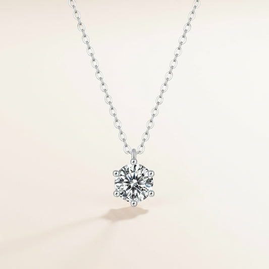 Sterling silver cable chain necklace with round moissanite solitaire in six-prong setting, styled on travertine stone.