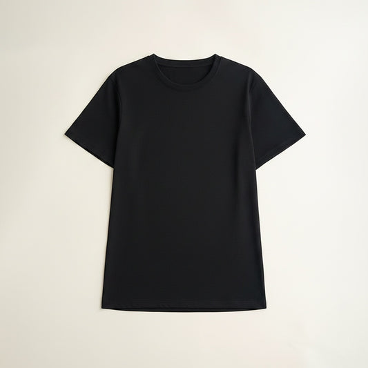Black short-sleeve crew-neck tee in Supima cotton styled with stone wide-leg trousers against a warm off-white plaster wall.