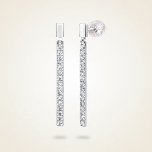 Polished silver linear bar drop earrings with pavé-set moissanite stones, styled on a warm off-white textured surface.