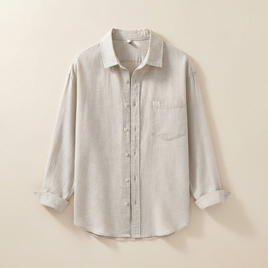 Woman in soft oatmeal button-up shirt and taupe trousers, styled in warm quiet-luxury studio light.
