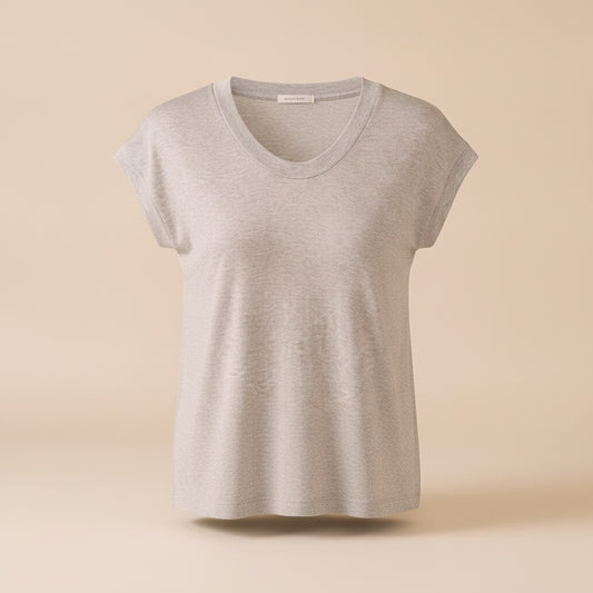 Woman in soft cap-sleeve knit top with scoop neckline, paired with tailored ecru trousers in a warm minimalist studio setting.