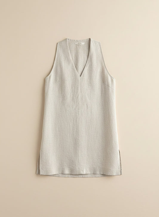 Ivory V-neck top styled with tonal taupe trousers on warm neutral studio backdrop, quiet-luxury minimal styling.