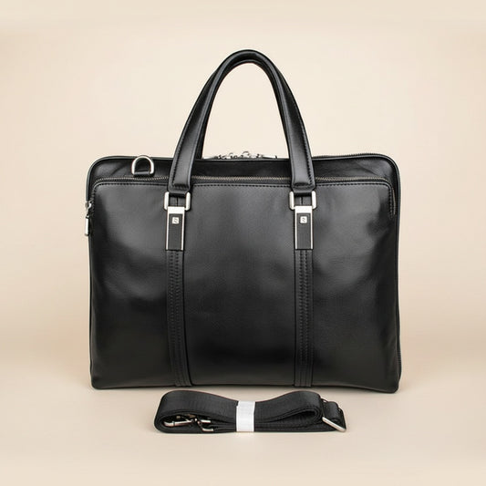 Structured black leather executive briefcase with twin top handles and silver hardware, styled on a travertine plinth in warm light.