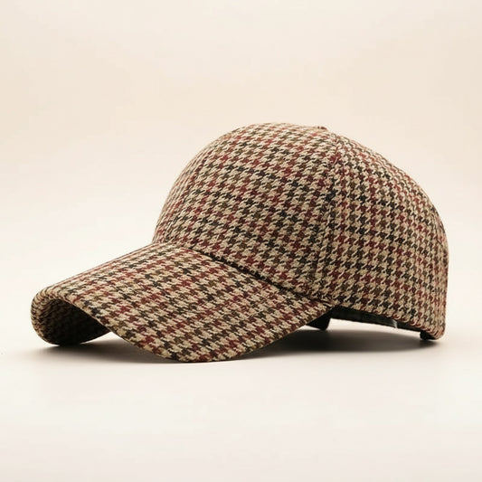 Six-panel houndstooth wool-blend cap in tobacco, oxblood and cream, curved brim, shown three-quarter on warm off-white.